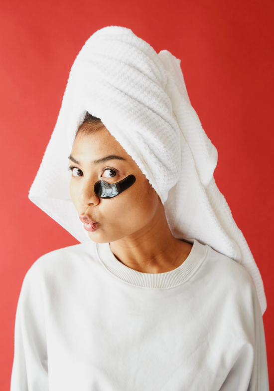 Young girl wearing eye gel pads on red background