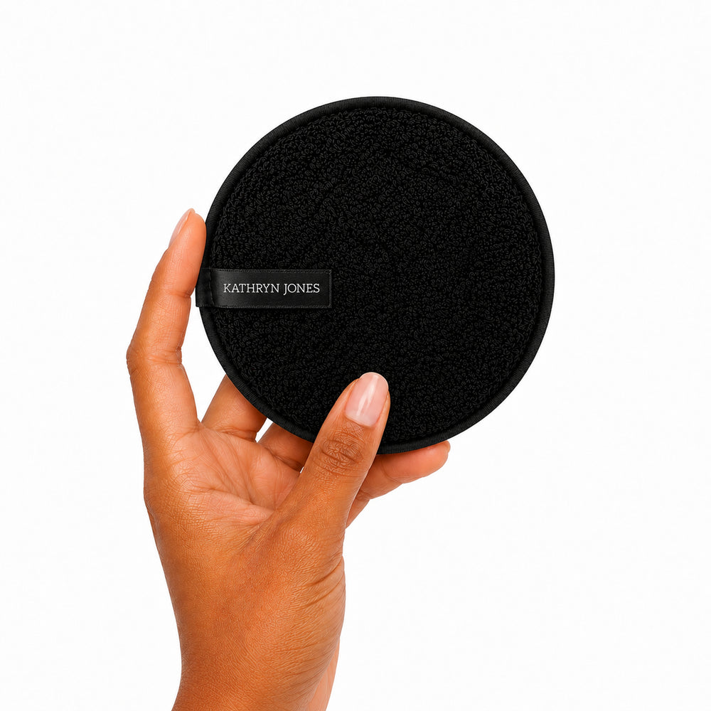 Hand holding a black circular product with 'Kathryn Jones' branding on a white background